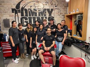 Tommy Guns Canberra ACT Staff by brand sign in shop